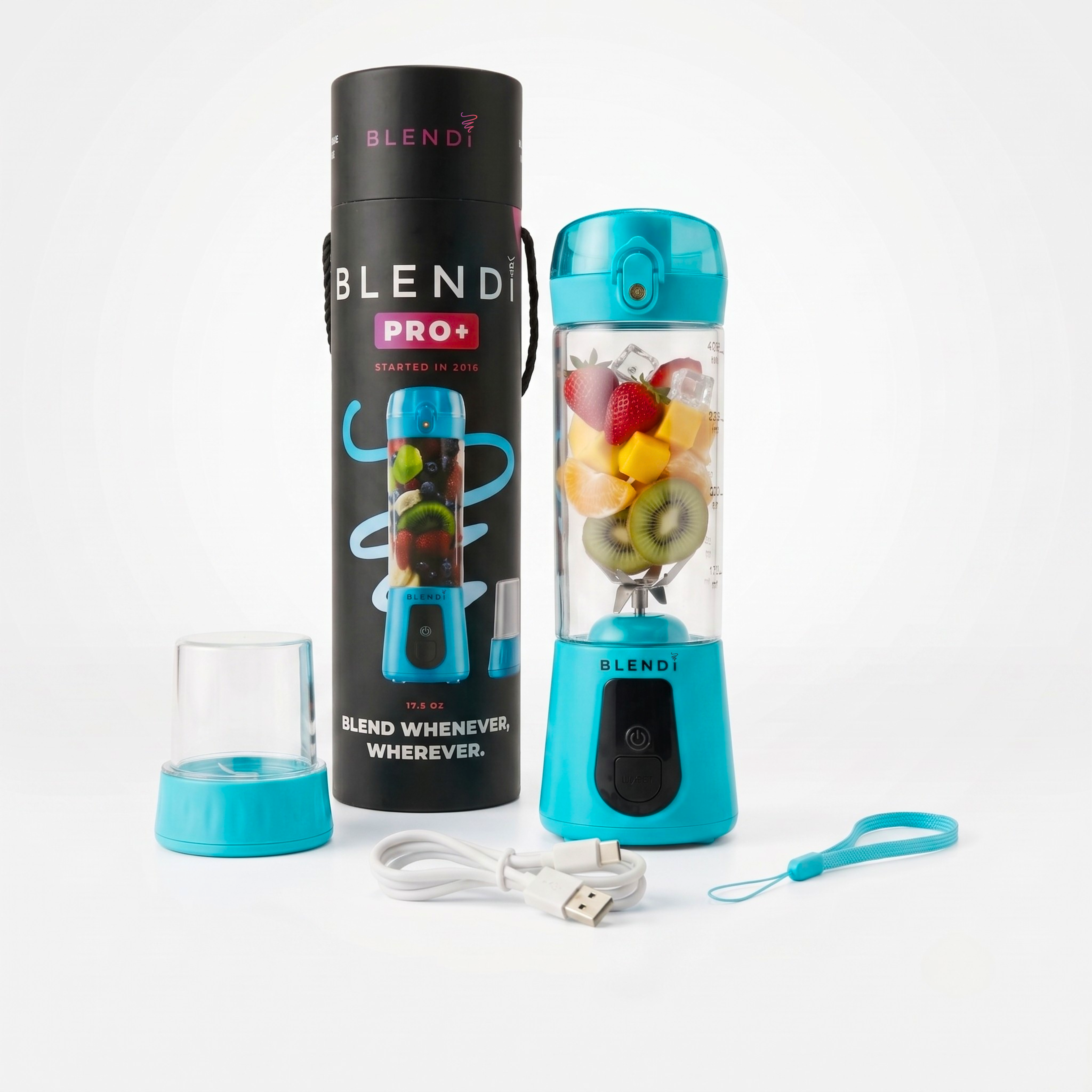 A portable personal blender set on a clean white background, featuring a turquoise and black Blender Pro+ blender bottle filled with fruit, its tall black packaging cylinder, a small clear travel cup, a white USB charging cable, and a turquoise carrying strap.