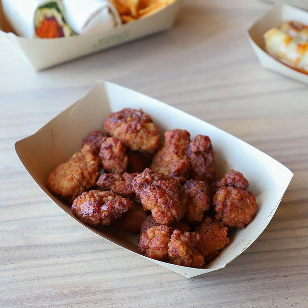 Crispy fried bite-sized chicken pieces served in a compostable paper food boat, perfect for takeout, concession stands, and casual dining.