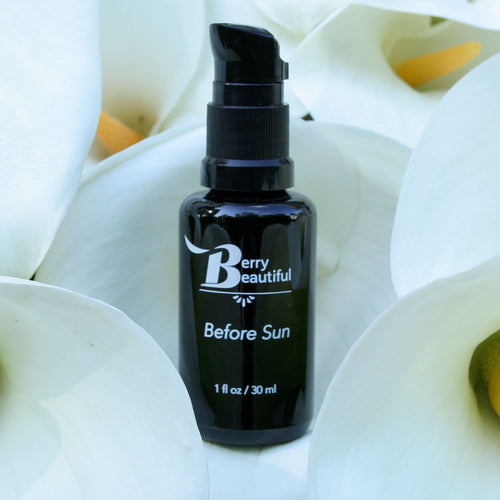 Black bottle labeled 'Berry Beautiful Before Sun' on a white floral background