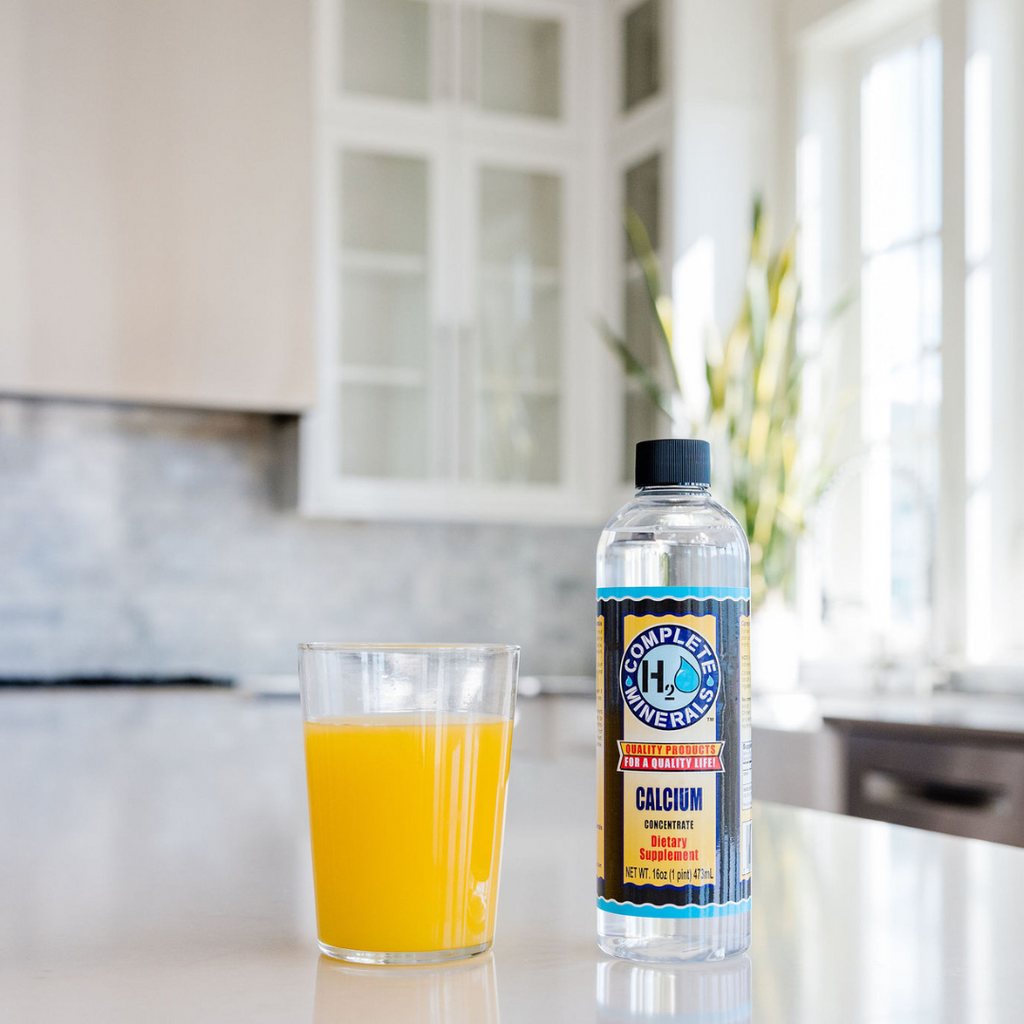Bottle of water and glass of orange juice on a kitchen counter