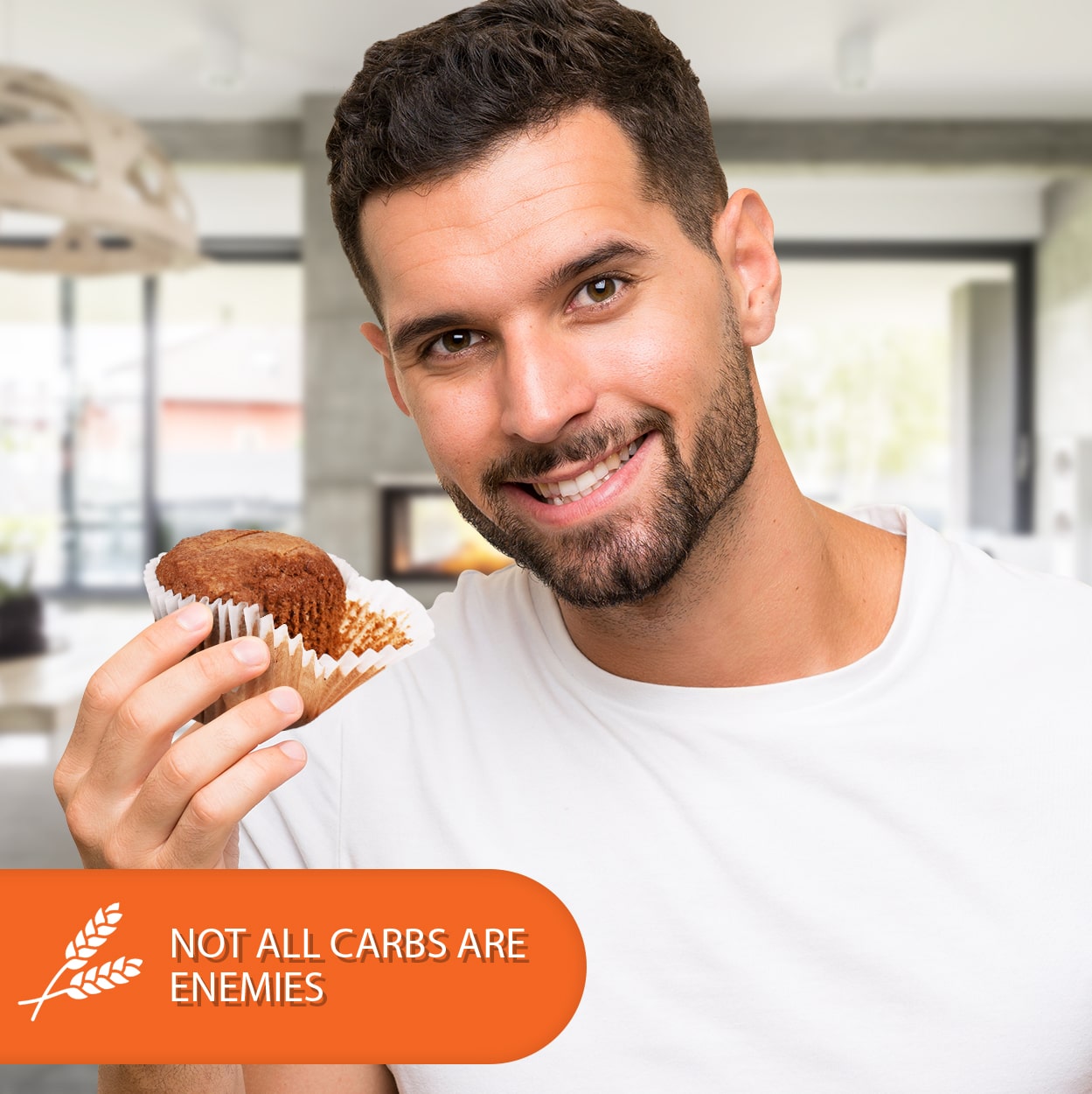 Man smiling while holding a cappuccino-flavored low-carb keto muffin with a "Not All Carbs Are Enemies" message, promoting sugar-free baking for keto and low-carb lifestyles.