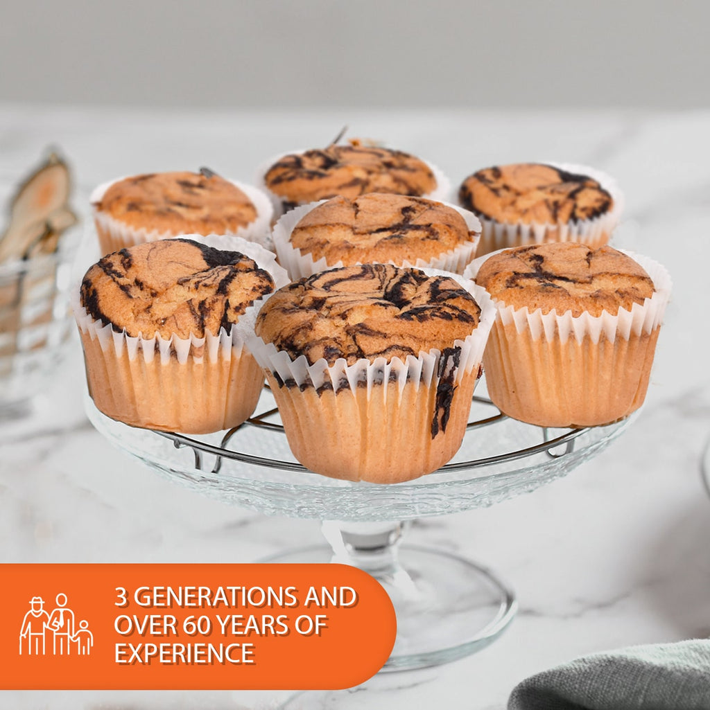 Low-carb marble muffins with chocolate swirls displayed on a glass cake stand, highlighting a sugar-free, keto-friendly bakery treat in a 6-pack.