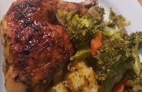 Certified Organic Pasture-Raised Chicken Leg Quarters served with broccoli, cauliflower, and carrots on a white plate.