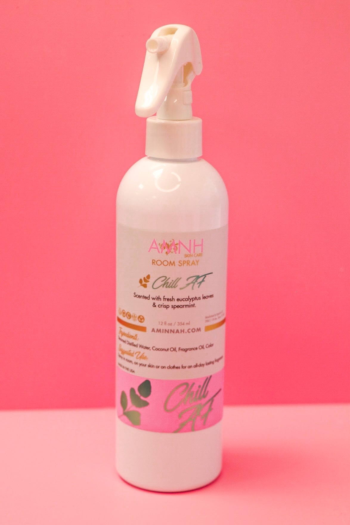 Chill AF Room Spray in a white spray bottle with eucalyptus and spearmint scent on a soft pink background by Aminnah, a female-owned clean beauty brand.