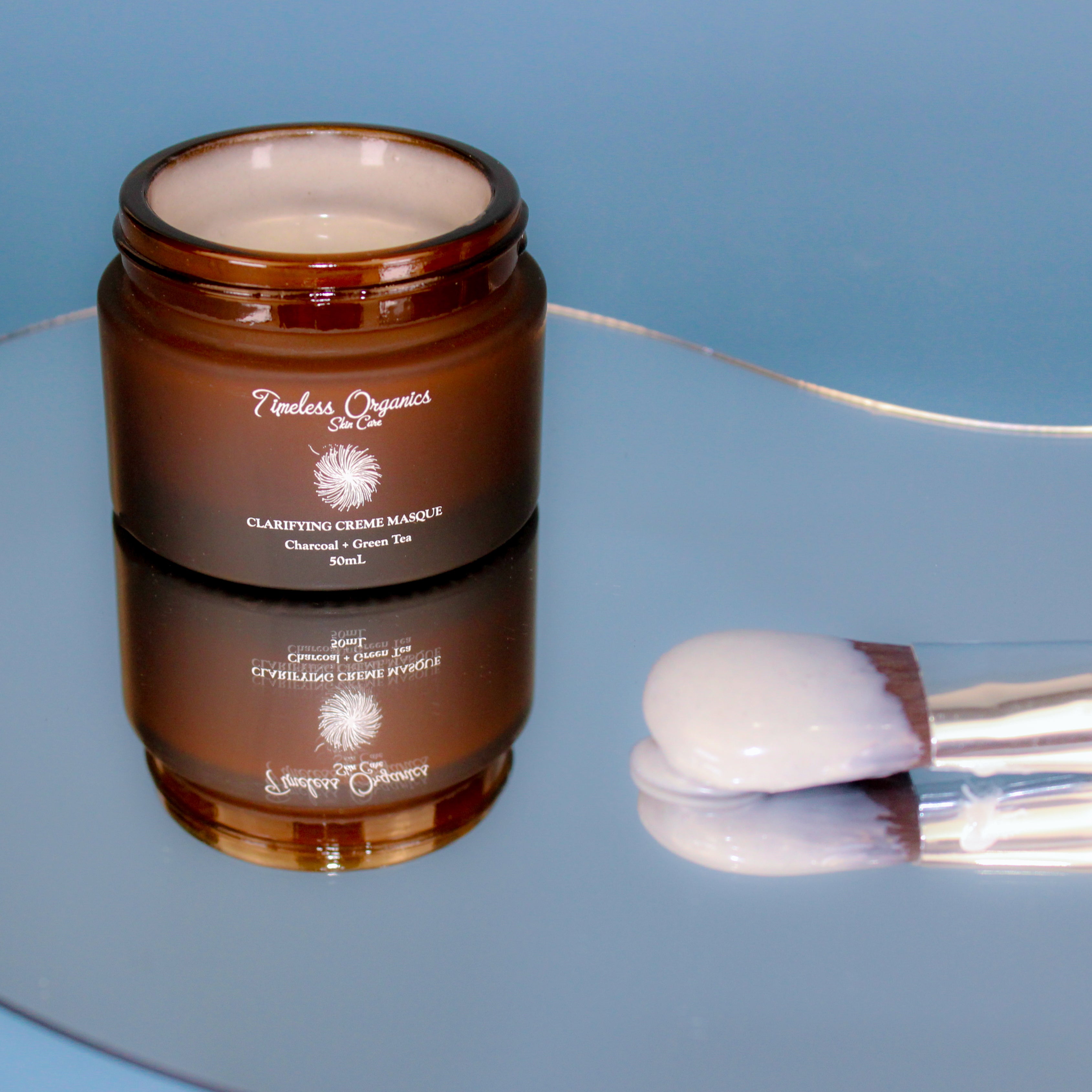 Brown jar of Timeless Organics cream on a reflective surface with a blue background