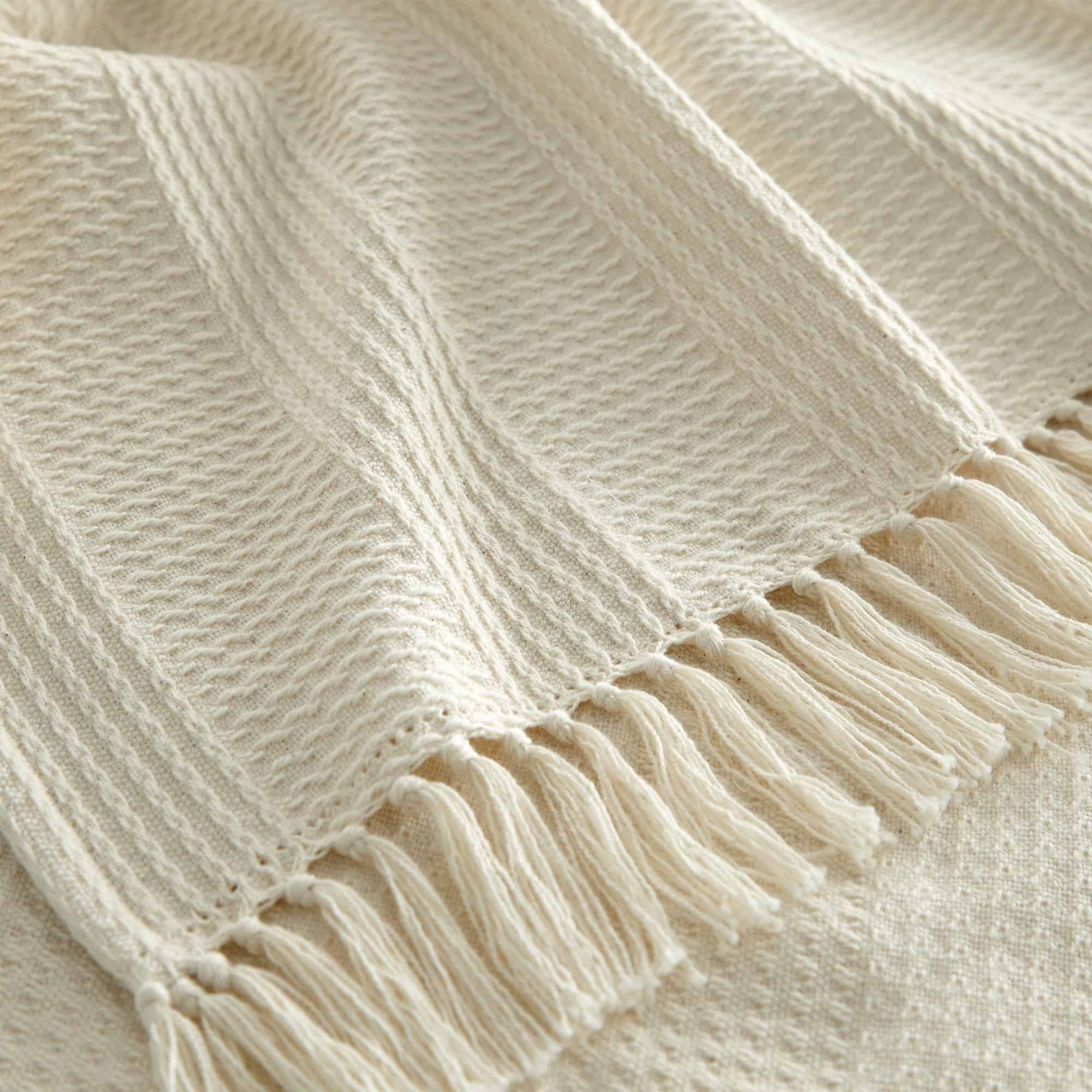 Close-up of a beige knitted blanket with fringes. Organic Cotton Throw with Tassels
