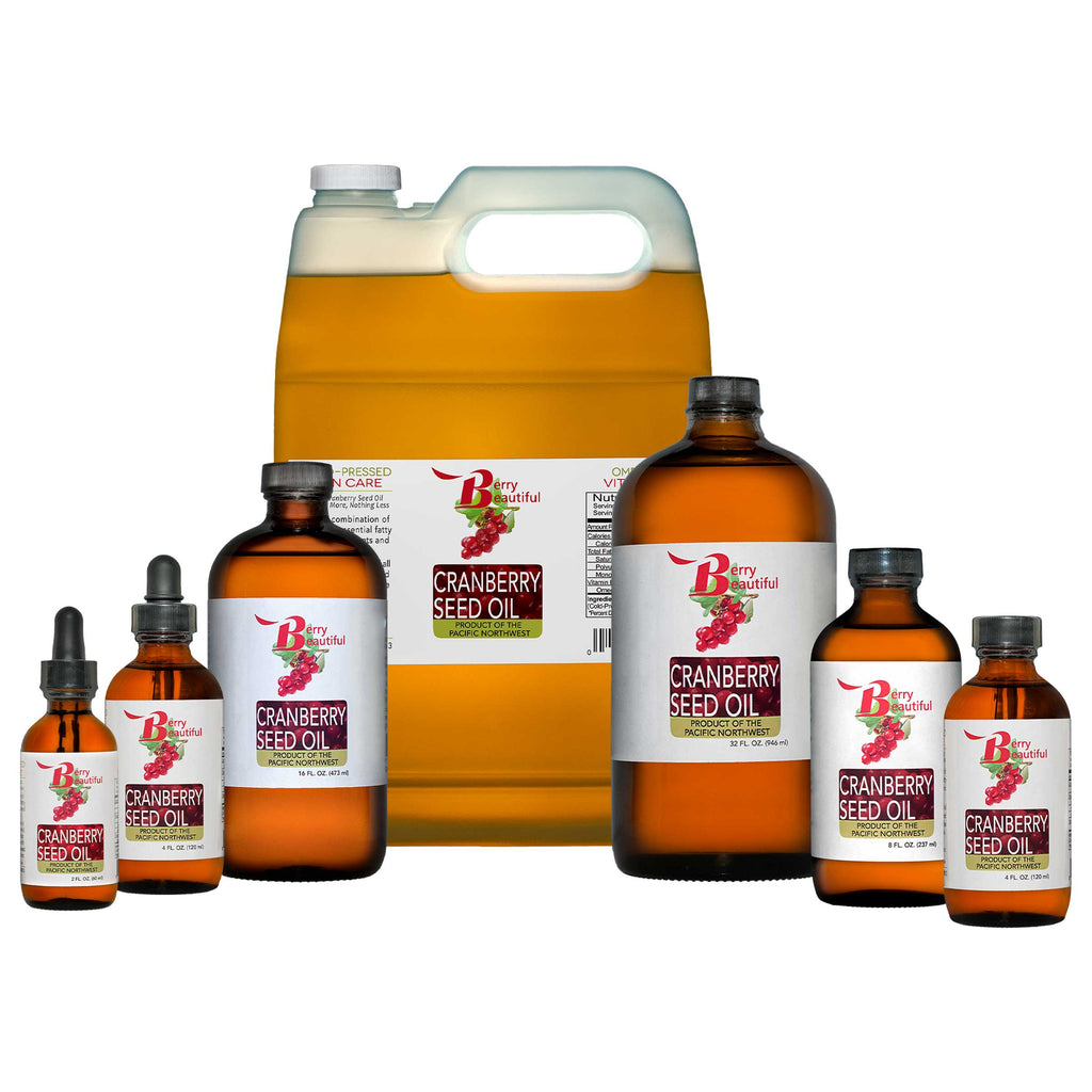 Collection of cranberry seed oil products including bottles and a gallon on a white background