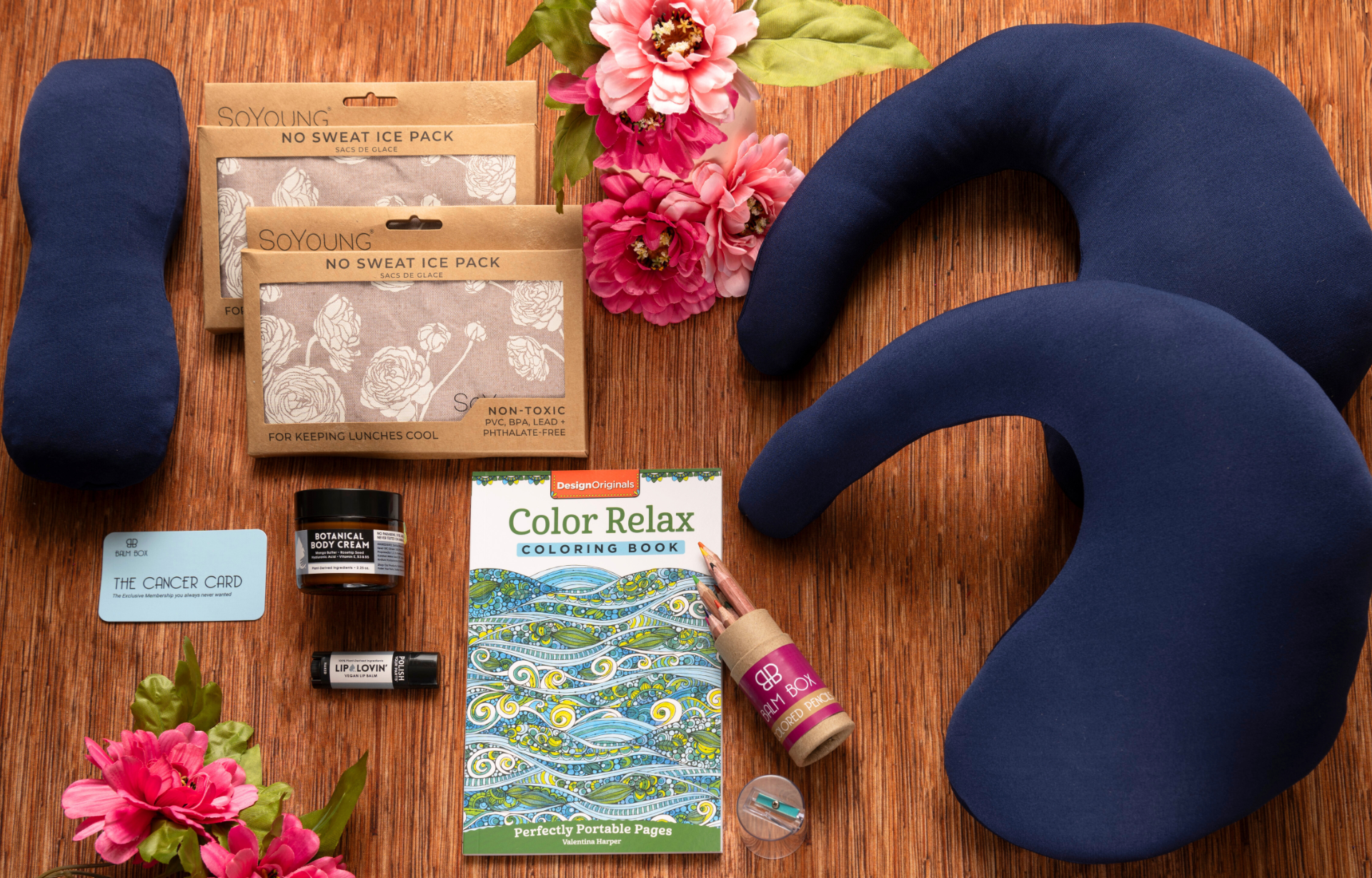 The Best Mastectomy Care Package featuring a thoughtful collection of mastectomy recovery essentials, self-care items, cooling eye masks, no-sweat ice packs, botanical balm, lip care, a relaxing coloring book, cancer support card, comfort accessories, and wellness gifts for women recovering from breast cancer surgery, mastectomy, chemotherapy, radiation, or cancer treatment, beautifully arranged on a warm wooden background with flowers.