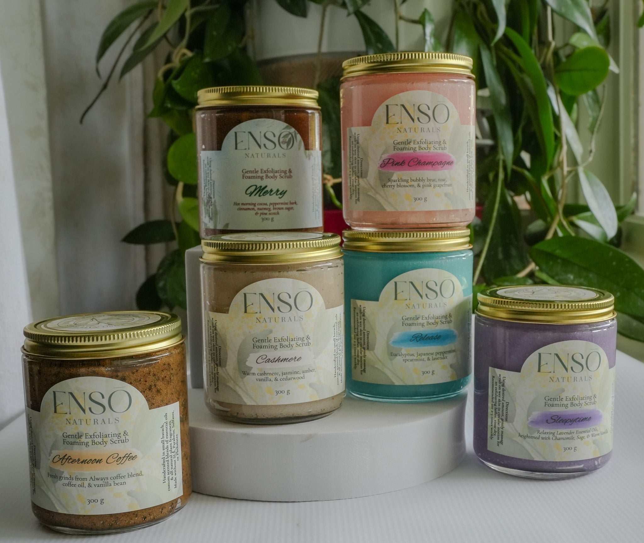 Enso Naturals gentle foaming sugar scrubs in colorful glass jars, natural exfoliating body scrubs for smooth, soft skin with assorted scents.