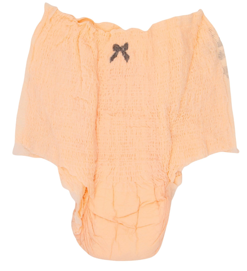 Light peach disposable baby diaper with a soft quilted design, stretch waistband, absorbent core, and a small black bow detail, isolated on a white background.