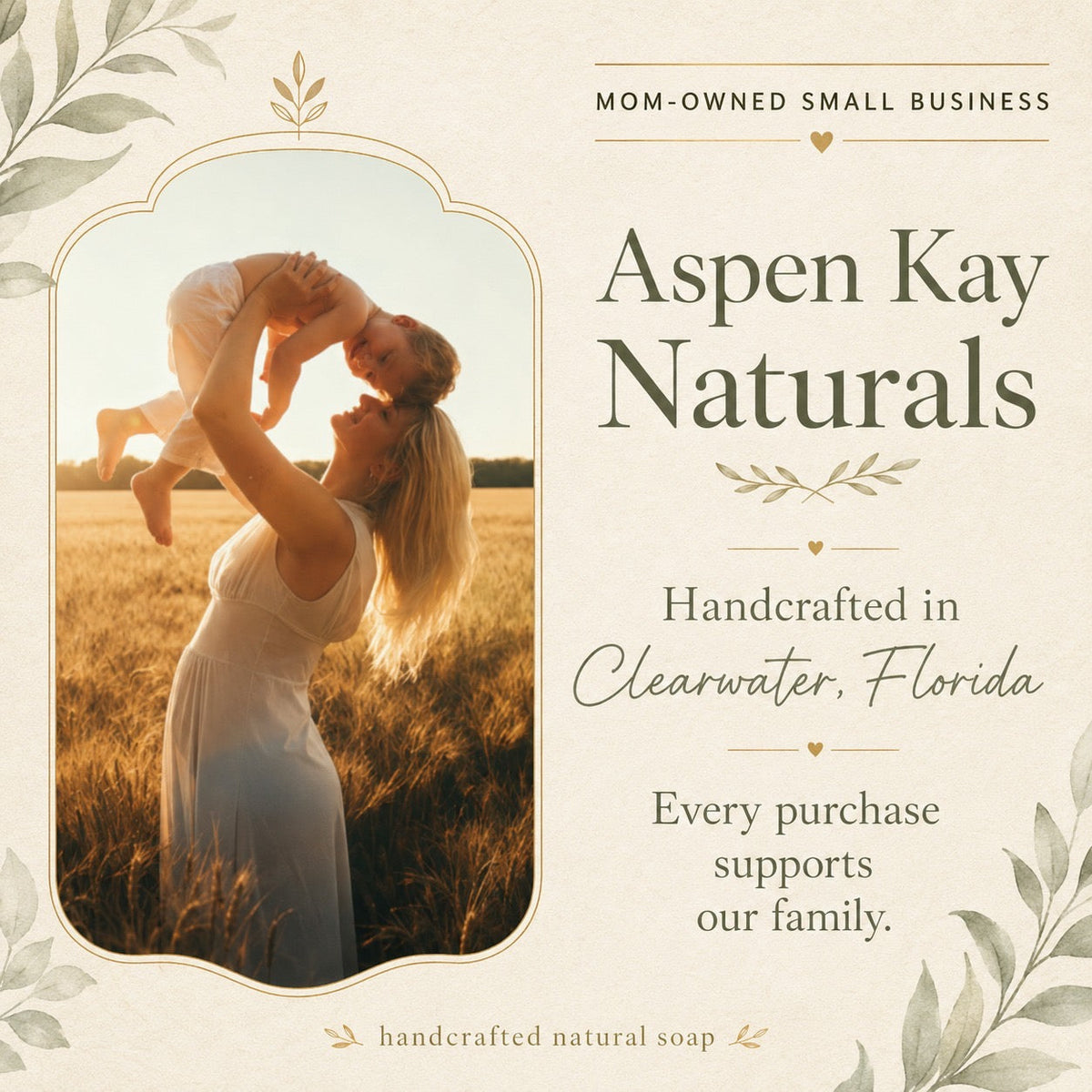 A promotional graphic for Aspen Kay Naturals handmade natural soap. The design features a warm cream background with elegant botanical leaf borders, a central arched photo frame showing a mother lifting her child in a sunlit field, and text highlighting that it is a mom-owned small business handcrafted in Clearwater, Florida.