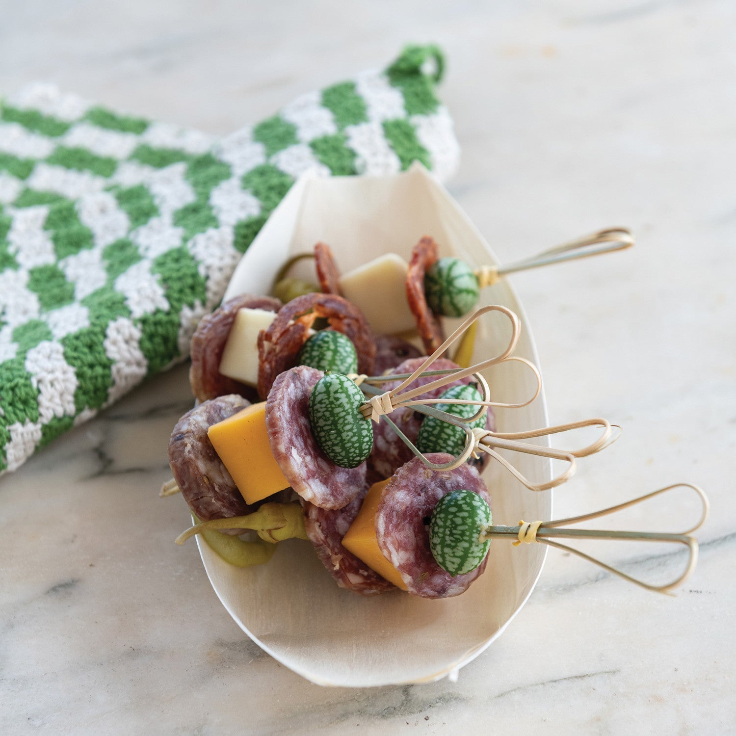 Platter of skewered appetizers with green garnishes on a marble surface. French Saucisson Sec Salumi | Finch + Fennel