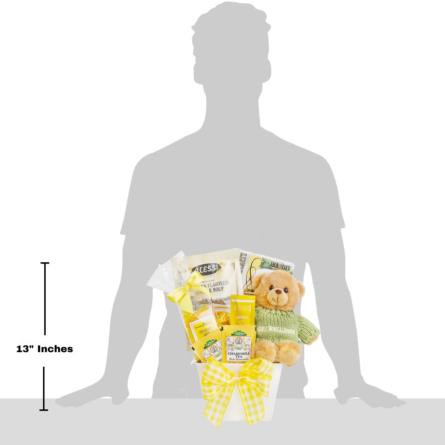 Gift basket with teddy bear and snacks on a silhouette of a person, showing size with '13 inches' label. Hugs & Well Wishes Gift Basket: Alessi Premium Chicken Flavored Noodle Soup, Artisan Olive Oil & Sea Salt Crackers, Butterscotch Candy, Chamomile Tea, 2 Honey Sticks, Plush Teddy Bear with “Get Well Soon” Sweater.