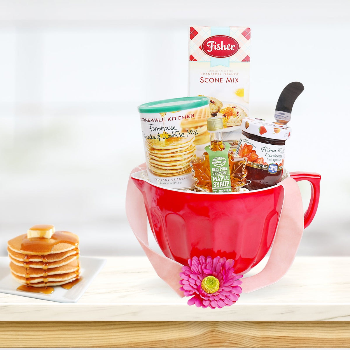 Red ceramic mixing bowl gift basket filled with pancake and waffle mix, cranberry orange scone mix, pure Vermont maple syrup, strawberry preserves, honey, spatula, and breakfast baking essentials on a white background. Home Made Morning Baking Gift Basket: Vermont Maple Syrup, Pancake &amp; Waffle Mix, Fisher Original Fair Scone &amp; Shortbread Mix, Fresh Fruit Jam, Stainless Steel Spread Knife, Red Mixing Bowl with Handle