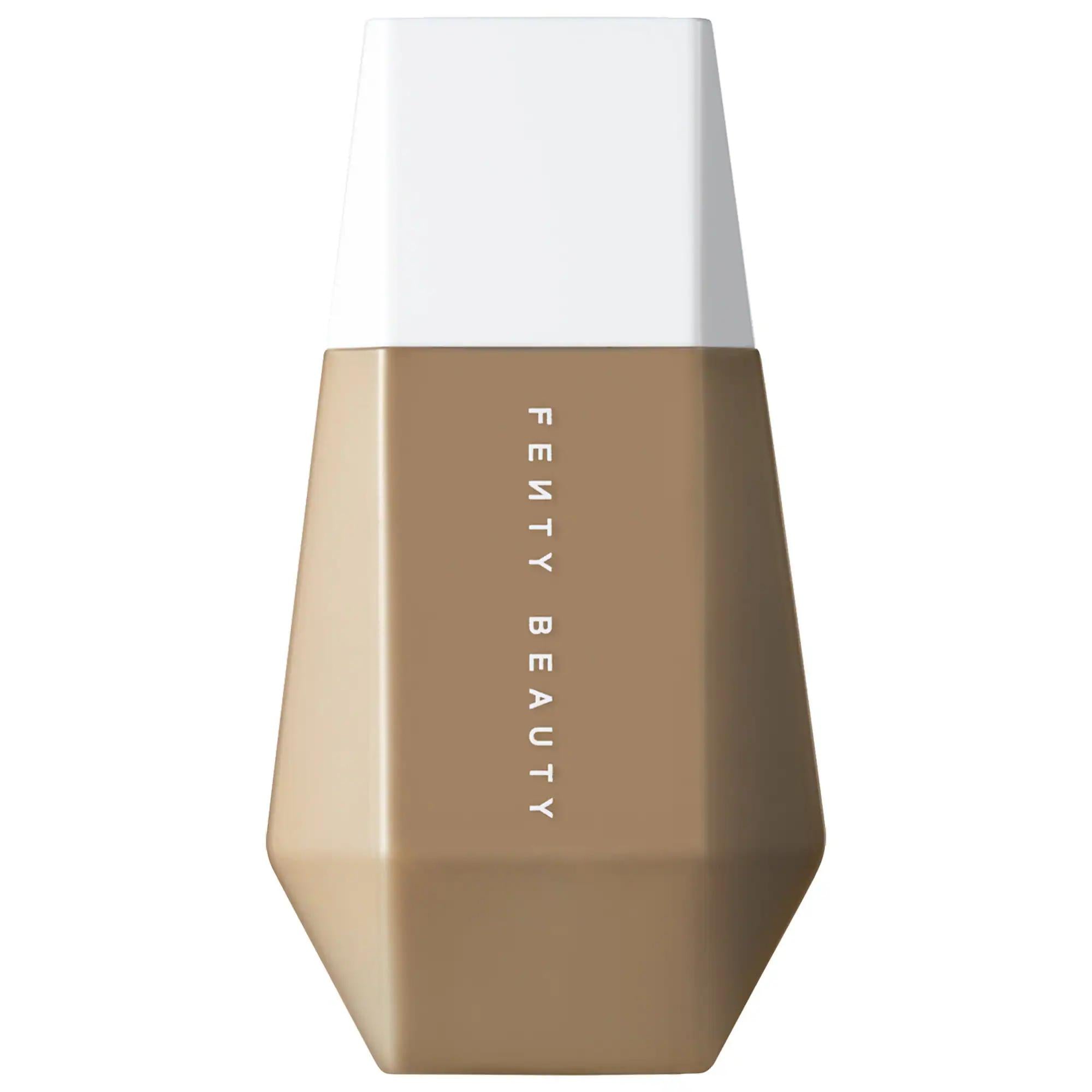 Fenty Beauty liquid foundation bottle with a faceted geometric design, featuring a warm medium tan shade on the lower half and a clean white cap on top, shown against a solid white background. Fenty Beauty Eaze Drop: Lightweight, Buildable Skin Tint Foundation for Natural, Blurred Finish | Vegan & Cruelty-Free