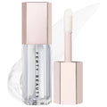 Fenty Beauty Clear Lip Tint in a clear bottle with a pale pink cap, shown next to its applicator wand on a white background with a soft pink smear. Fenty Beauty Gloss Bomb: Universal Lip Luminizer - Explosive Shine, Hydrating & Non-Sticky Formula for All Skin Tones