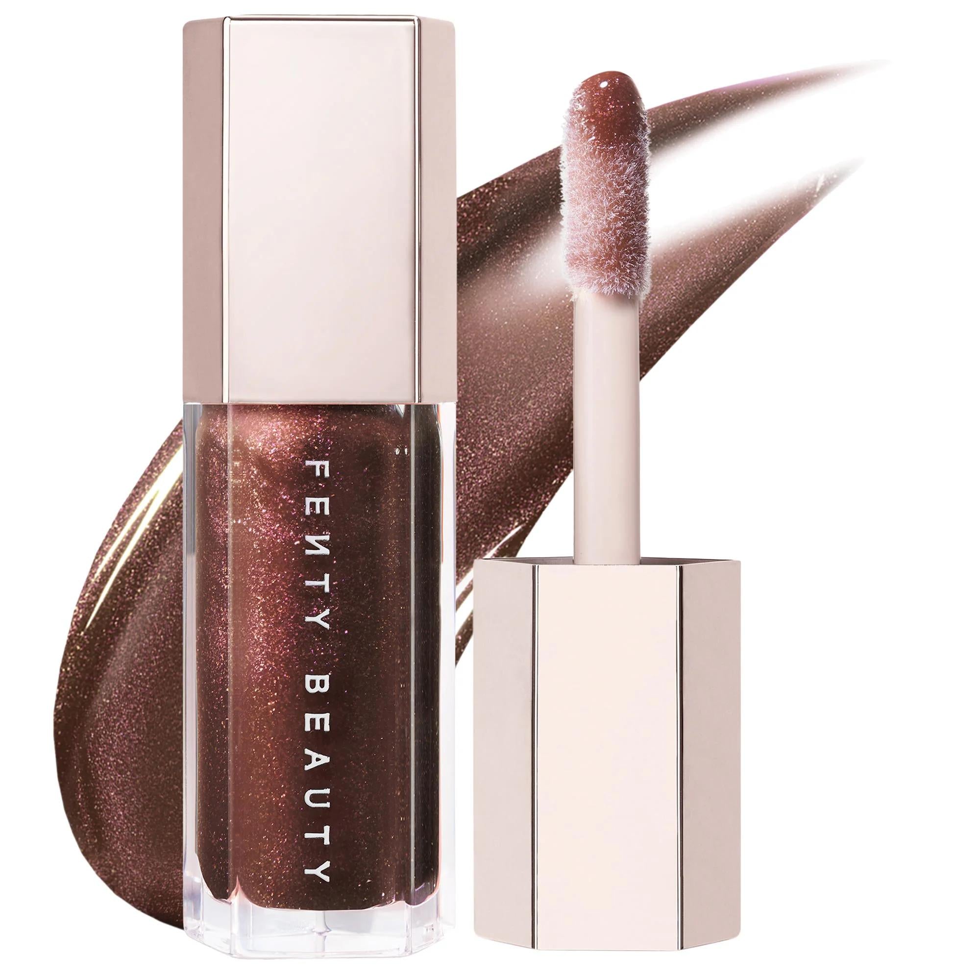 Fenty Beauty liquid lipstick in a metallic bronze-brown shade, shown with the cap off and the applicator wand against a white background with a matching product smear. Fenty Beauty Gloss Bomb: Universal Shine Lip Luminizer - Non-Sticky, Hydrating Peach Vanilla Lip Gloss for All Skin Tones
