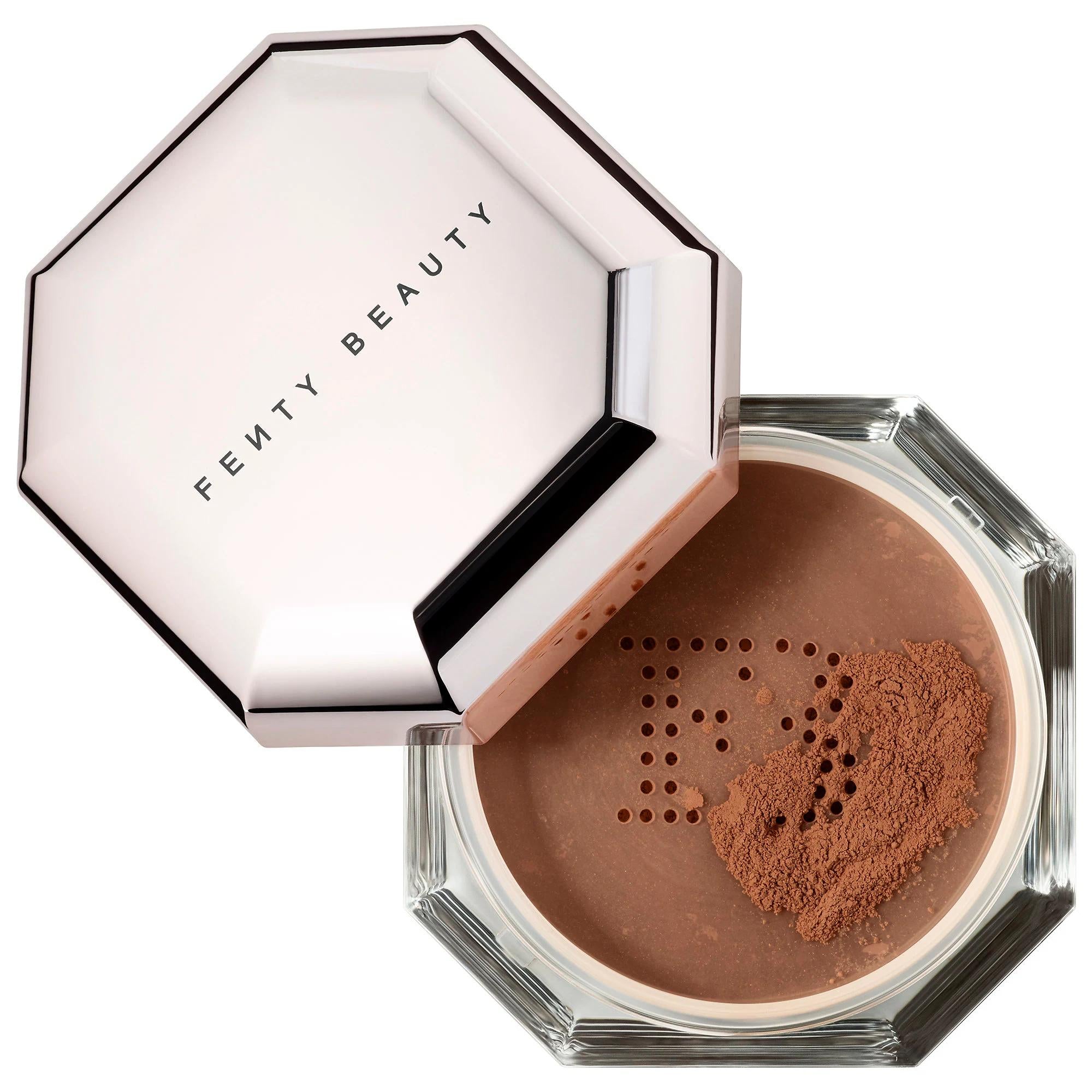 Fenty Beauty Pressed Powder Foundation in a hexagonal clear jar with a metallic rose gold lid, shown open with the lid resting beside the compact on a white background. Fenty Beauty Pro Filt'r: Weightless Loose Setting Powder for Shine Control & Photo-Ready Perfection - Cruelty-Free