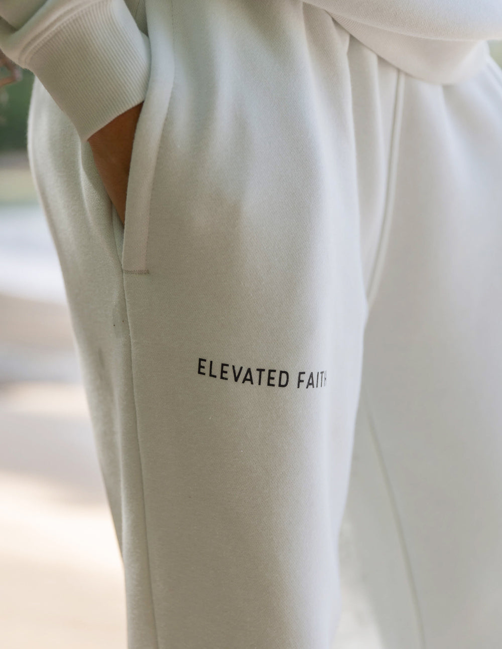 White sweatshirt with 'ELEVATED FAITH' text on a blurred background