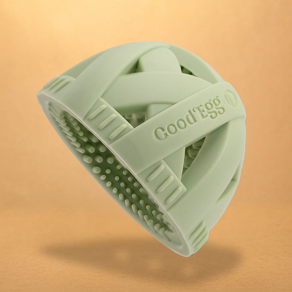 Original GoodEgg Brush™ in soft sage green featuring a seamless food-grade silicone design, ergonomic cross-strap grip, and 650+ flexible scrubbing nubs for gently cleaning fresh chicken, duck, goose, and quail eggs.