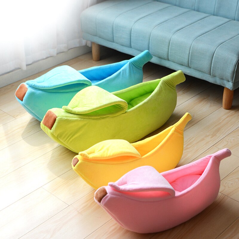 Four colorful banana-shaped pet beds on a wooden floor with a light blue sofa in the background.