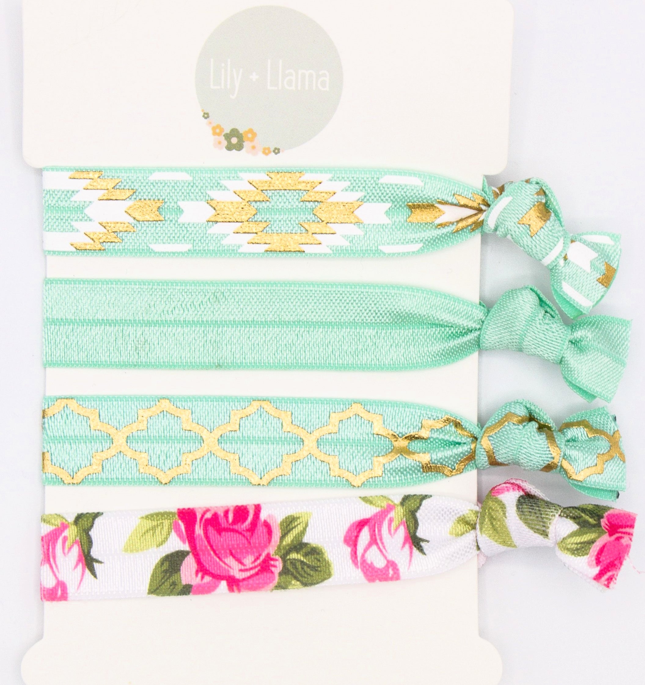 Set of four soft elastic hair ties in mint green with gold geometric patterns, solid mint, and pink floral print on a Lily + Llama display card.