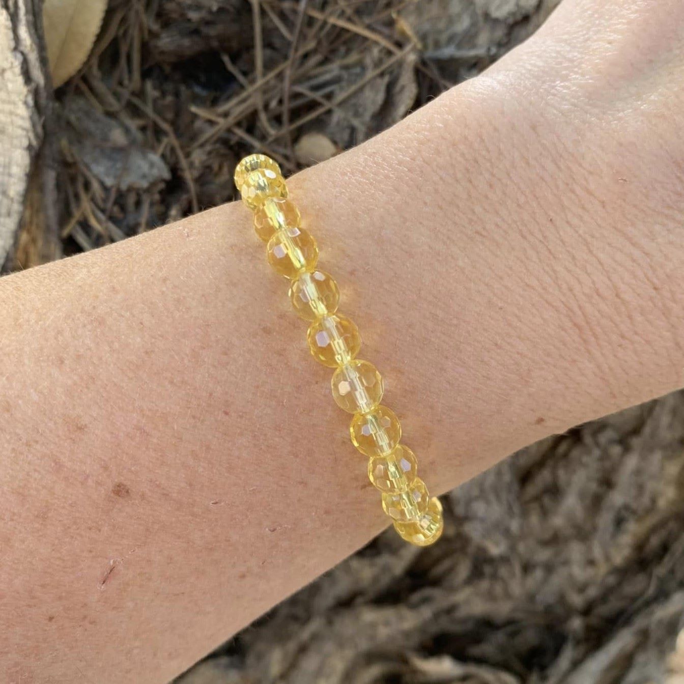 Yellow beaded bracelet on a wrist with a natural background. Citrine Bracelet 6 mm Faceted Round Beads – Abundance and Cheer