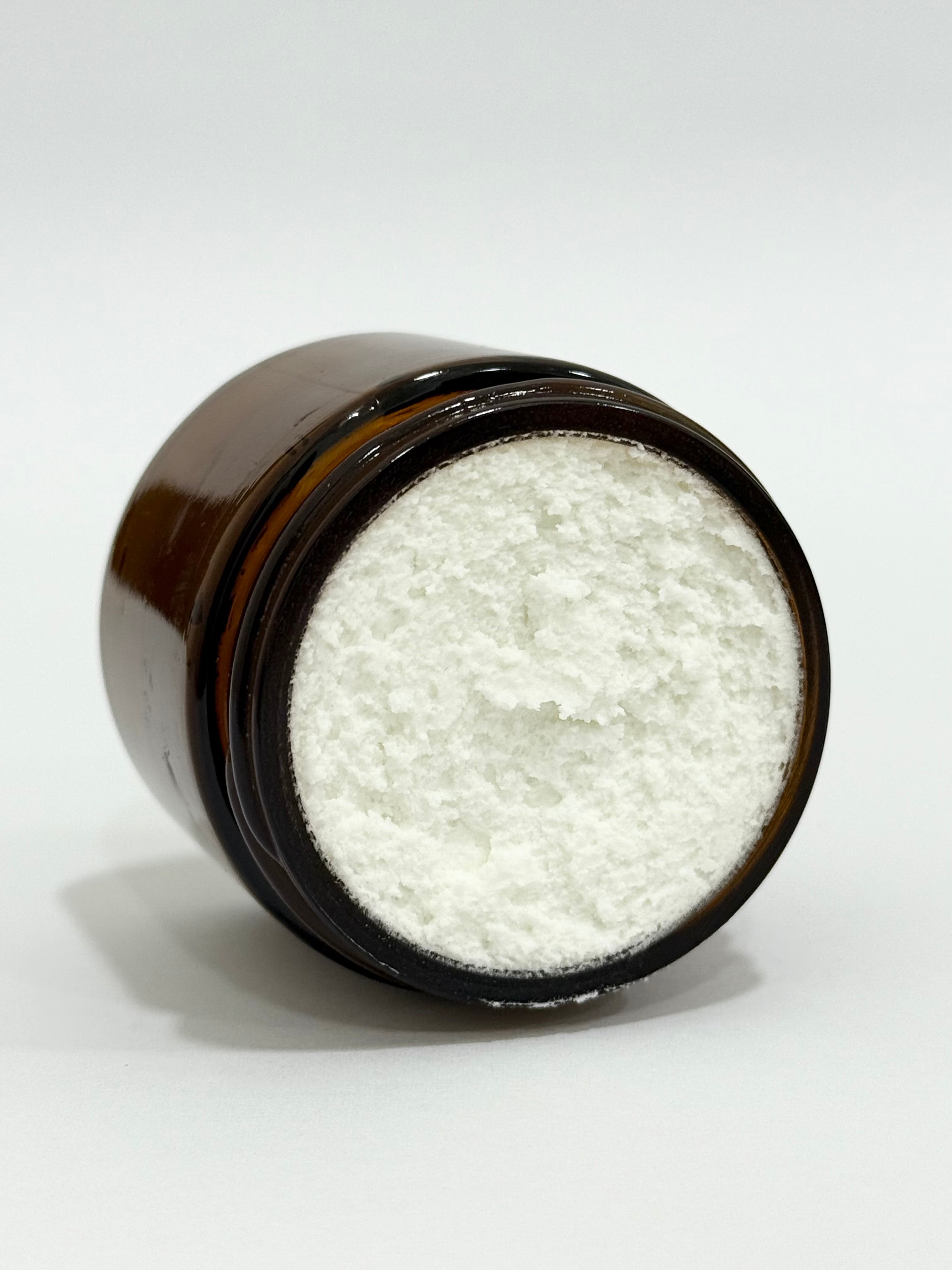 Brown jar filled with white powder on a white background
