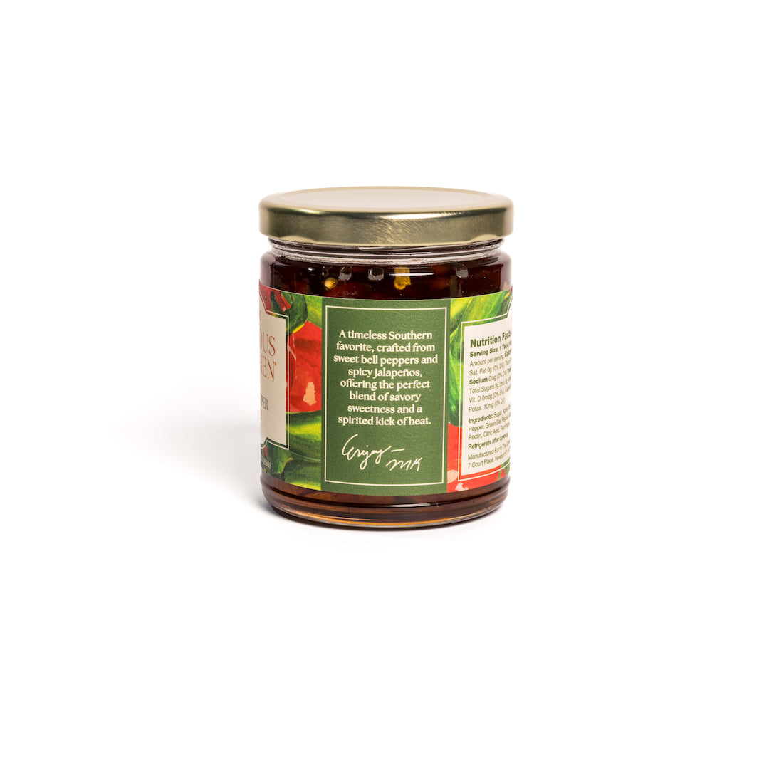 Back view of In the Curious Kitchen Hot Pepper Jelly jar showing the product story, nutrition facts, ingredients, and gold lid on a white background.