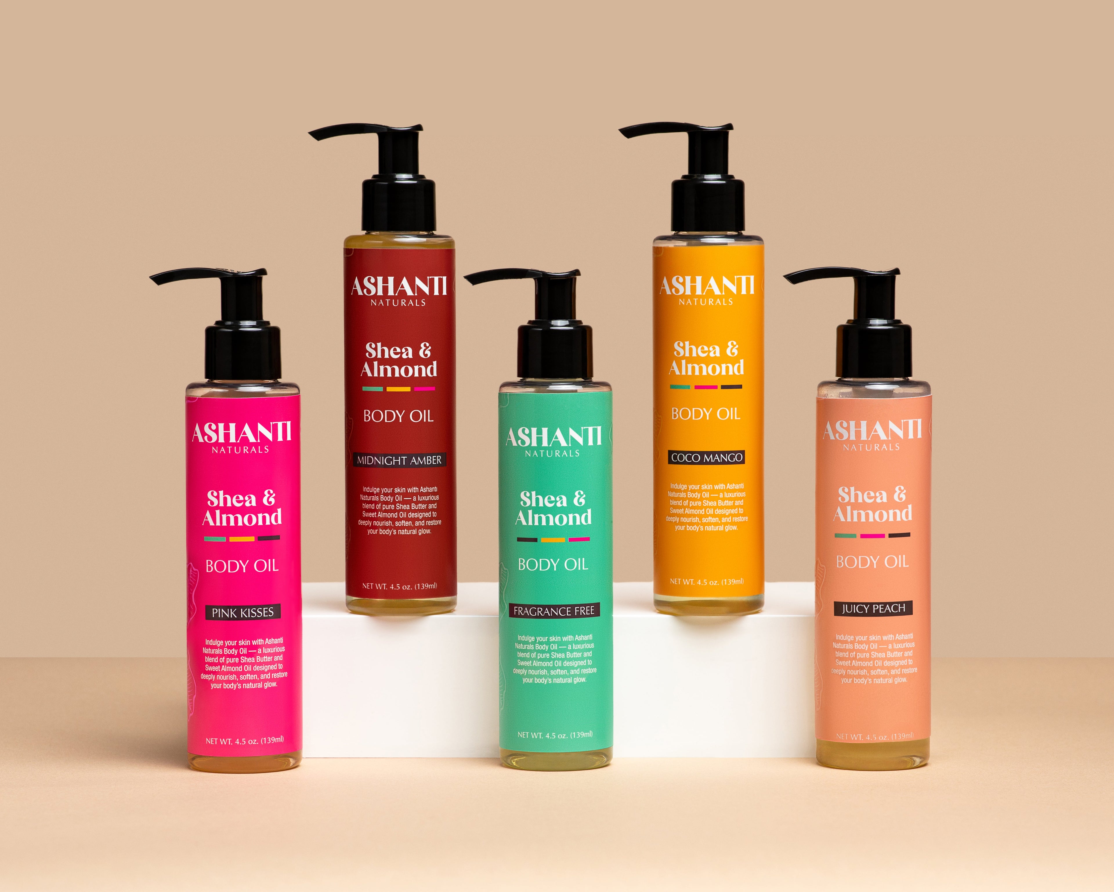 Ashanti Naturals Shea & Sweet Almond Body Oil collection featuring Fragrance Free, Pink Kisses, Midnight Amber, Coco Mango and Juicy Peach scents, moisturizing body oil with shea butter and sweet almond oil, lightweight natural skin moisturizer for dry skin, nourishing clean beauty skincare on beige background