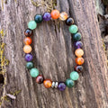 Multicolored beaded bracelet on a wooden surface. Abundance & Motivation Vibes Bracelet