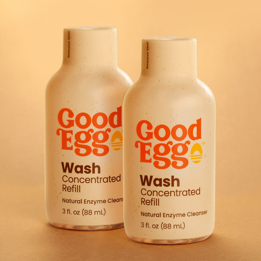 Two bottles of GoodEgg Wash Concentrated Refill natural enzyme egg cleanser on a beige background.