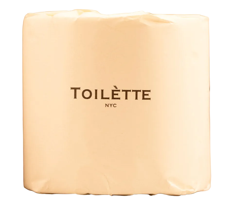 A cream-colored paper towel holder canister with the brand name 'TOILÈTE NYC' printed in dark brown on the front, set against a neutral beige background.
