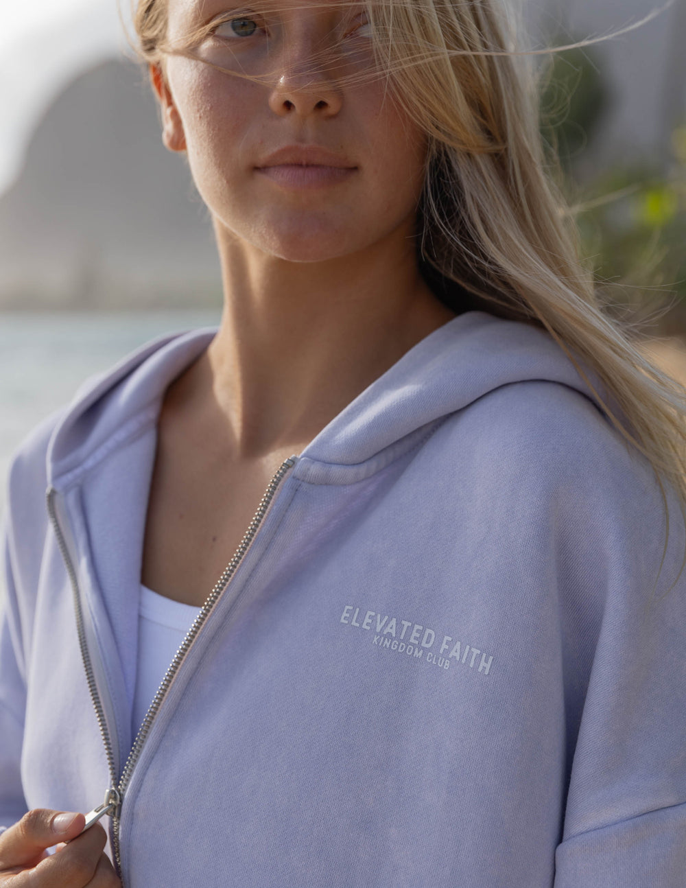 Woman wearing a light purple hoodie with 'Elevated Faith' branding.
