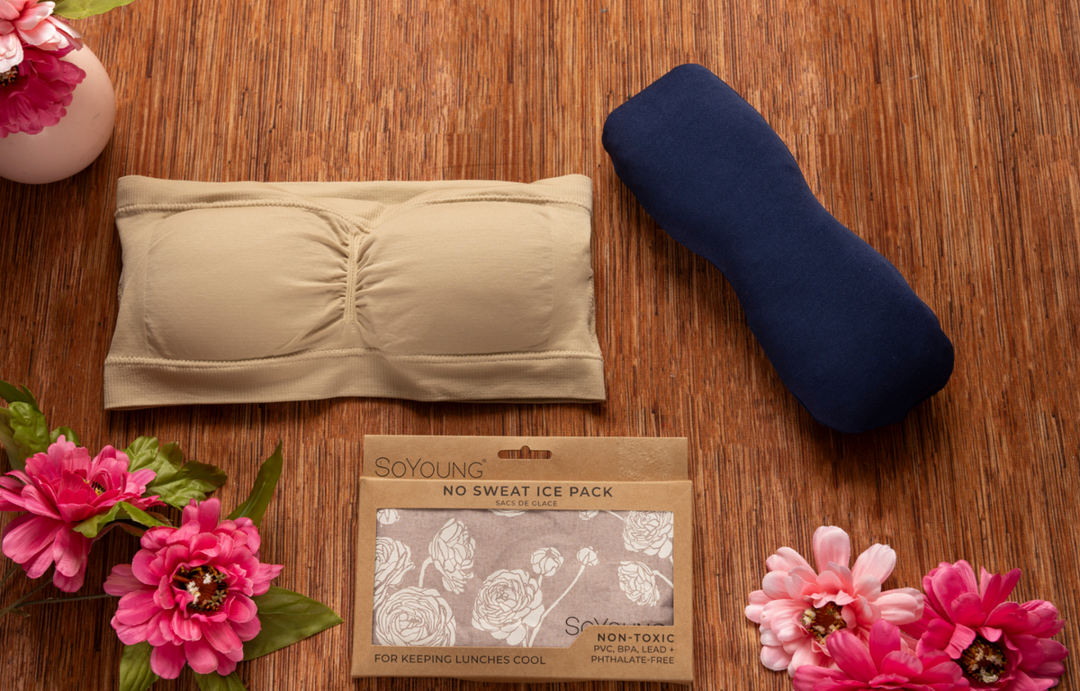 The Ideal Lumpectomy Care Package featuring a supportive beige breast care bandeau, navy reusable ice pack, SoYoung No Sweat Ice Pack, soft recovery essentials, cooling comfort accessories, post-lumpectomy self-care supplies, breast surgery recovery gift, breast cancer support gift for women, mastectomy recovery comfort, healing wellness care package, thoughtful recovery gift set beautifully arranged on a warm wooden surface with realistic pink flowers.