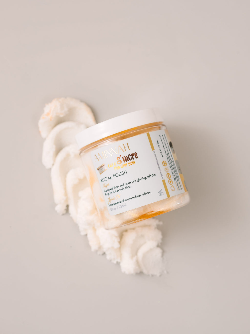 Toasted Marshmallow Sugar Scrub by AMINNAH with 24K gold dust on a clean white background, clean beauty exfoliating body scrub made with natural ingredients, vegan, cruelty-free, paraben-free, gluten-free skincare, female-owned brand, recyclable packaging, luxurious self-care gift, moisturizing body polish for soft glowing skin.