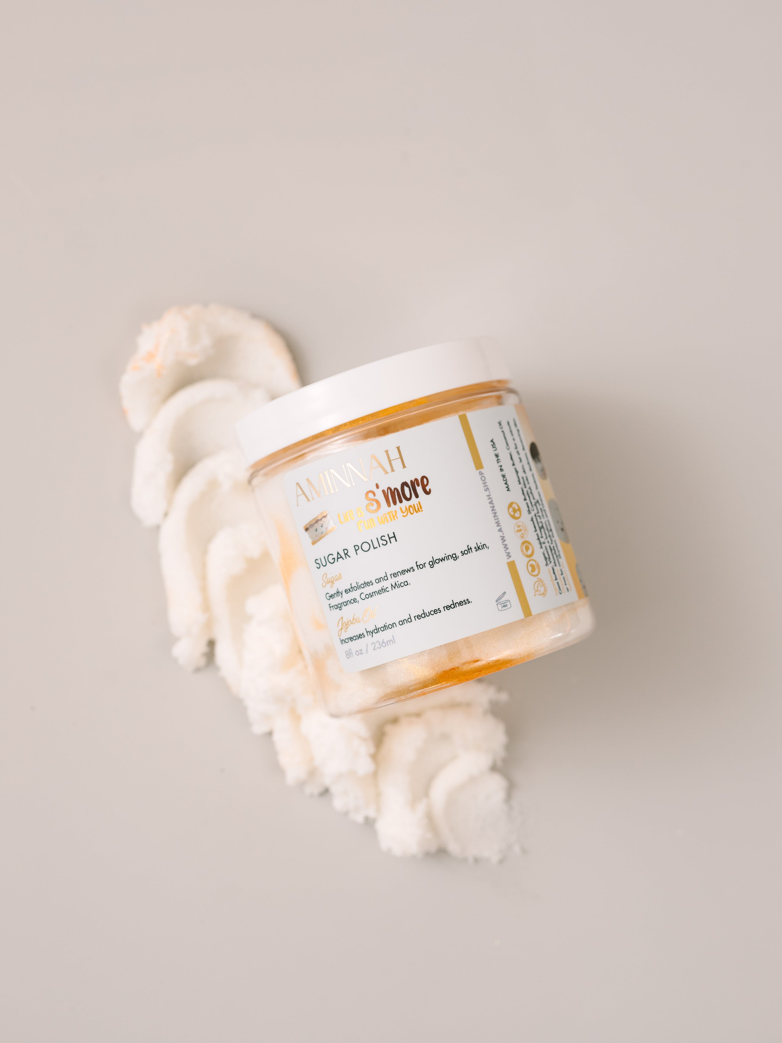 Toasted Marshmallow Sugar Scrub by AMINNAH with 24K gold dust on a clean white background, clean beauty exfoliating body scrub made with natural ingredients, vegan, cruelty-free, paraben-free, gluten-free skincare, female-owned brand, recyclable packaging, luxurious self-care gift, moisturizing body polish for soft glowing skin.