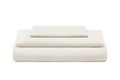 A stack of three folded sheets or bedding pieces in a solid off-white color, arranged neatly on a pure white background. Organic Sateen Bed Sheets Set