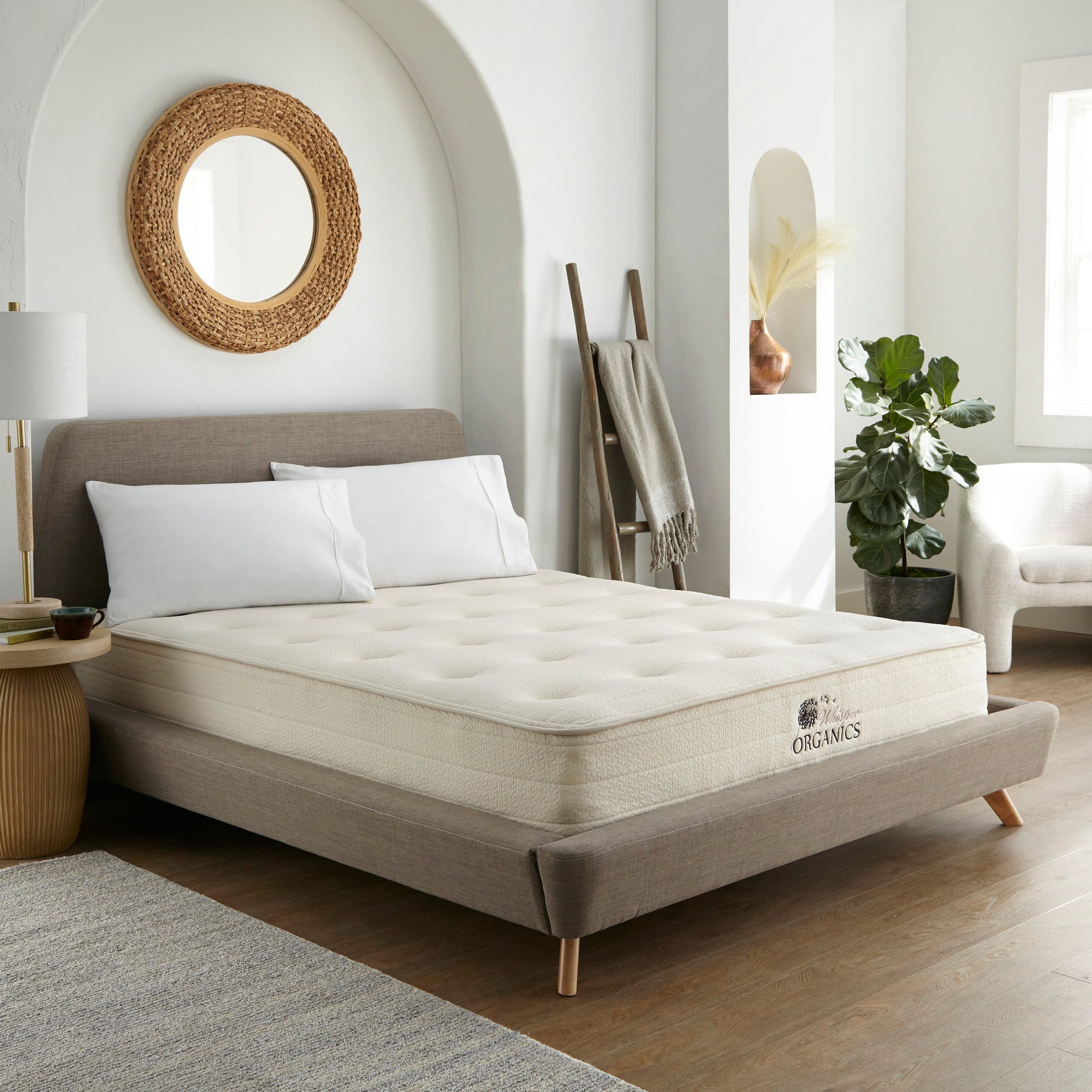 Bed with a mattress in a bedroom setting, Mattress on a bed in a bedroom with 'Whitney Organics' branding. 100% GOTS & GOLS-Certified organic cotton, wool and latex, 10" profile: 2" organic Dunlop latex + 7-zone pocketed coils, Medium feel for that “just right” balance of comfort + support, Breathable organic wool & cotton cover for airflow and temperature regulation, Lumbar support with zoned coil design, Suitable for an adjustable base & Made with sustainable, renewable materials, Made in the USA