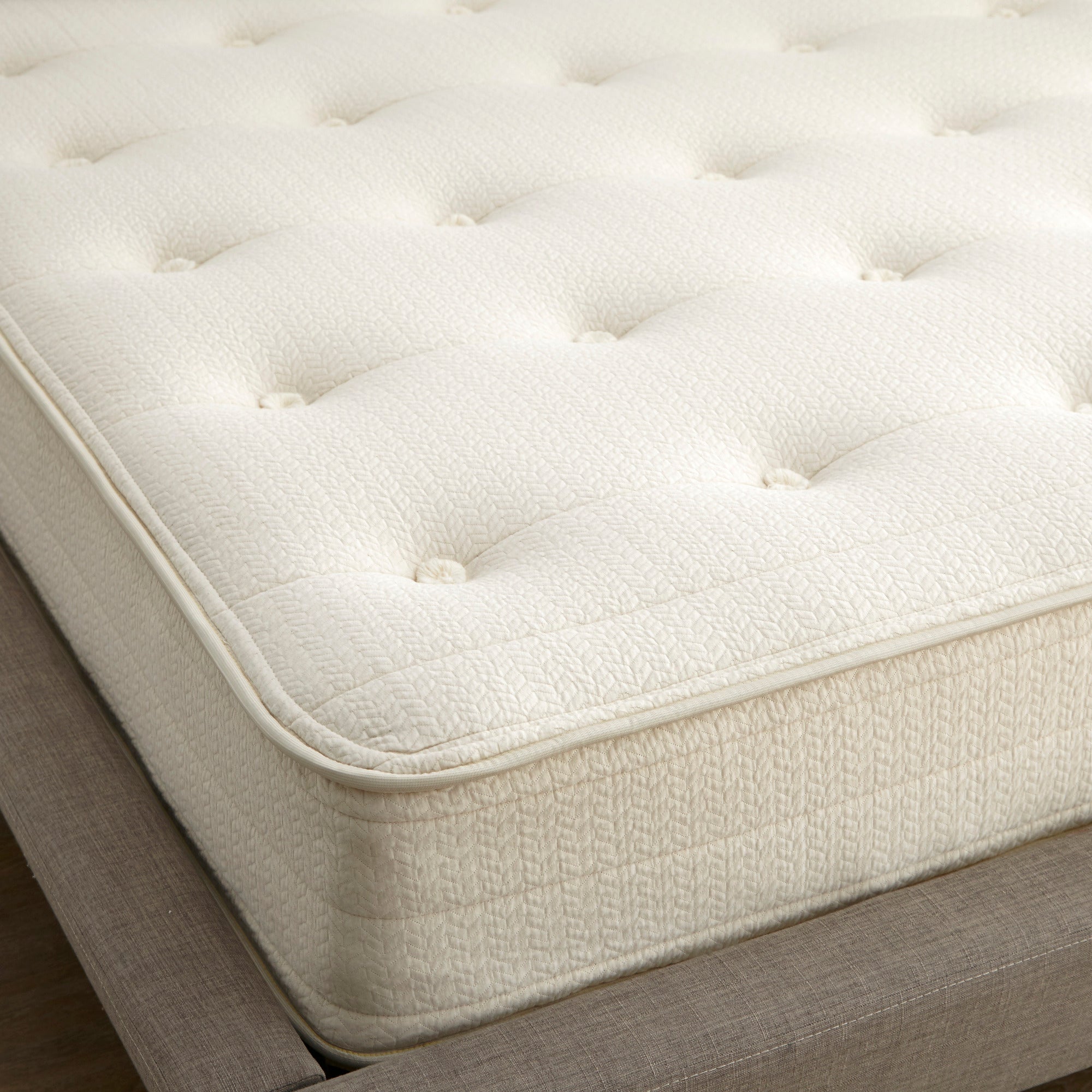 Close-up of a white tufted mattress on a wooden bed frame. Mattress on a bed in a bedroom with 'Whitney Organics' branding. 100% GOTS & GOLS-Certified organic cotton, wool and latex, 10" profile: 2" organic Dunlop latex + 7-zone pocketed coils, Medium feel for that “just right” balance of comfort + support, Breathable organic wool & cotton cover for airflow and temperature regulation, Lumbar support with zoned coil design, Suitable for an adjustable base & Made with sustainable, renewable materials, USA