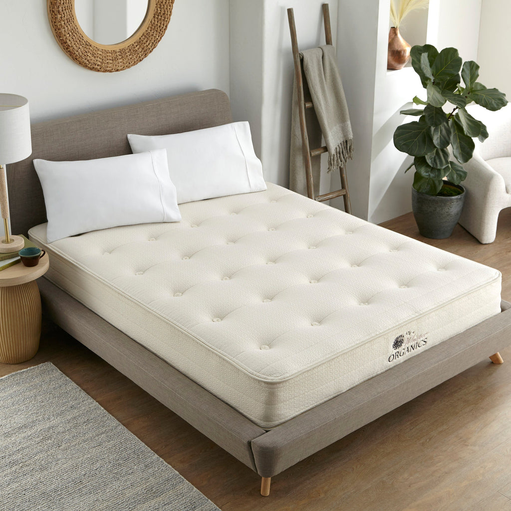 Mattress on a bed in a bedroom setting with decor elements. 100% GOTS & GOLS-Certified organic cotton, wool and latex, 10" profile: 2" organic Dunlop latex + 7-zone pocketed coils, Medium feel for that “just right” balance of comfort + support, Breathable organic wool & cotton cover for airflow and temperature regulation, Lumbar support with zoned coil design, Suitable for an adjustable base & Made with sustainable, renewable materials, Made in the USA