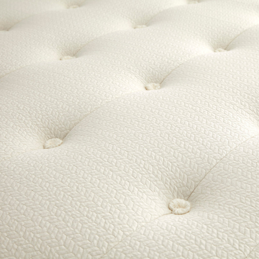 Close-up of a textured white mattress surface, Mattress on a bed in a bedroom with 'Whitney Organics' branding. 100% GOTS & GOLS-Certified organic cotton, wool and latex, 10" profile: 2" organic Dunlop latex + 7-zone pocketed coils, Medium feel for that “just right” balance of comfort + support, Breathable organic wool & cotton cover for airflow and temperature regulation, Lumbar support with zoned coil design, Suitable for an adjustable base & Made with sustainable, renewable materials, Made in the USA