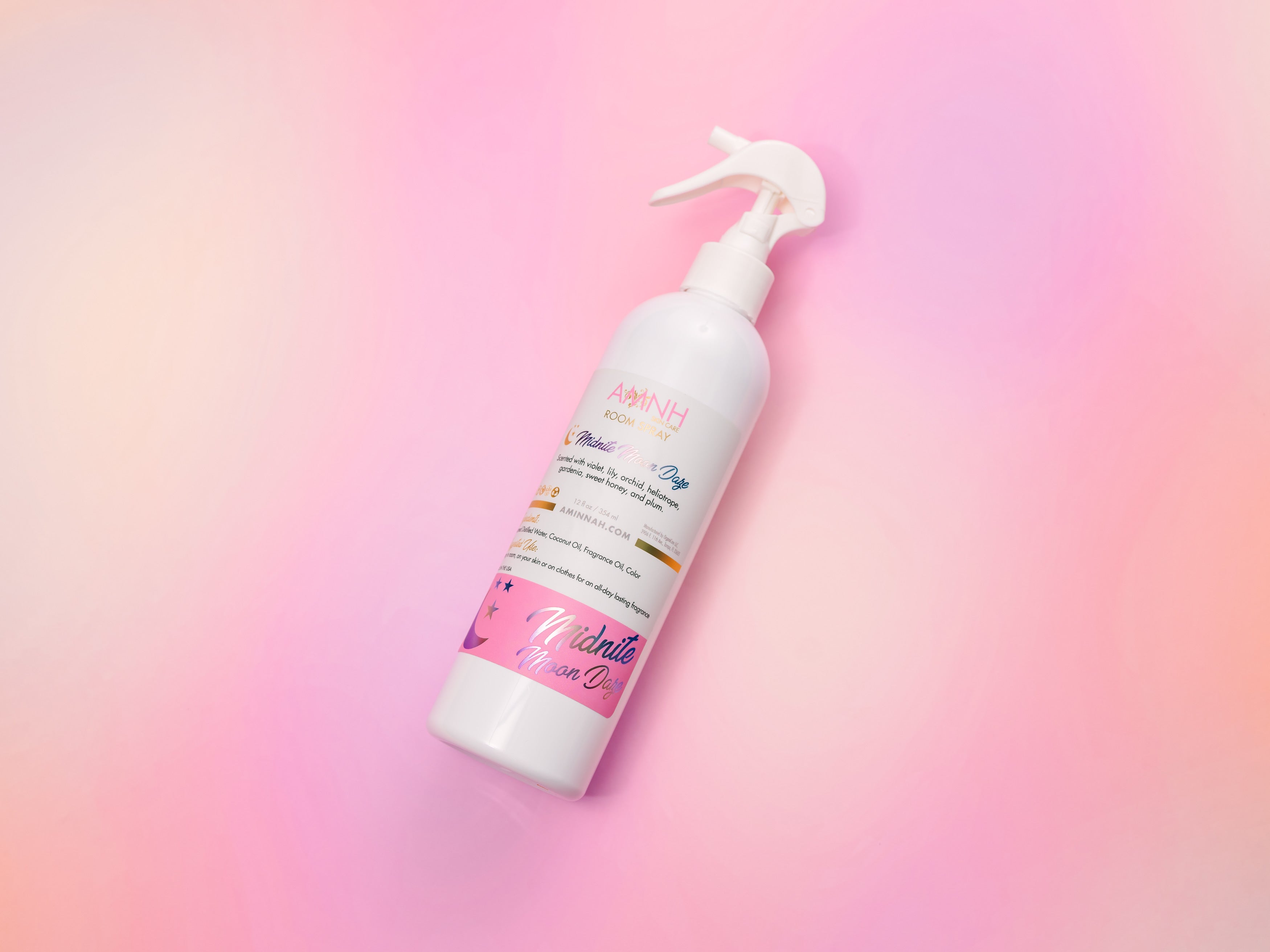 AMINNAH Midnite Moon Daze Room Spray bottle displayed on a soft pink and lavender gradient background. Clean beauty, cruelty-free, vegan room spray crafted with naturally derived ingredients including steamed distilled water, coconut oil, and fragrance oil to refresh rooms, linens, and fabrics. Female-owned brand available at Tree of Life Grocers.