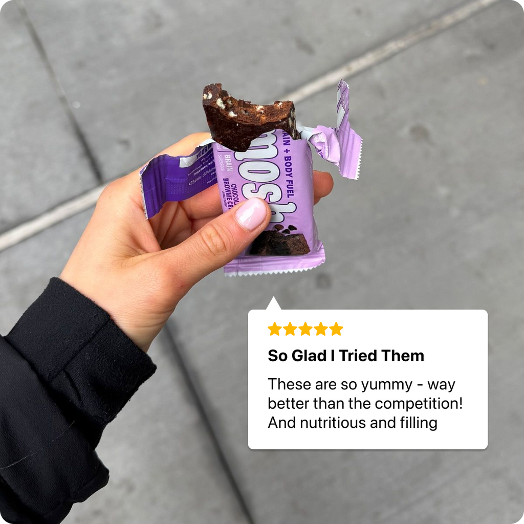 Hand holding a chocolate bar with a review text overlay on a gray pavement background