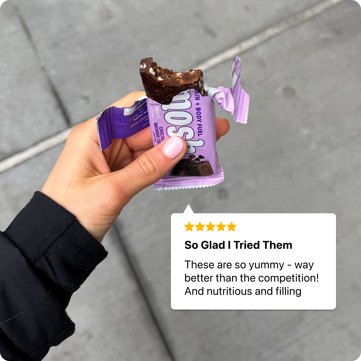 Hand holding a chocolate bar with a review text overlay on a gray pavement background