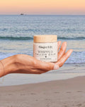Organic Whipped Ginger Lily Tallow Balm in hand at the beach, 100% grass-fed organic beef tallow moisturizer for face and body, natural whipped balm for dry, sensitive skin with nourishing clean skincare and ocean sunset background.