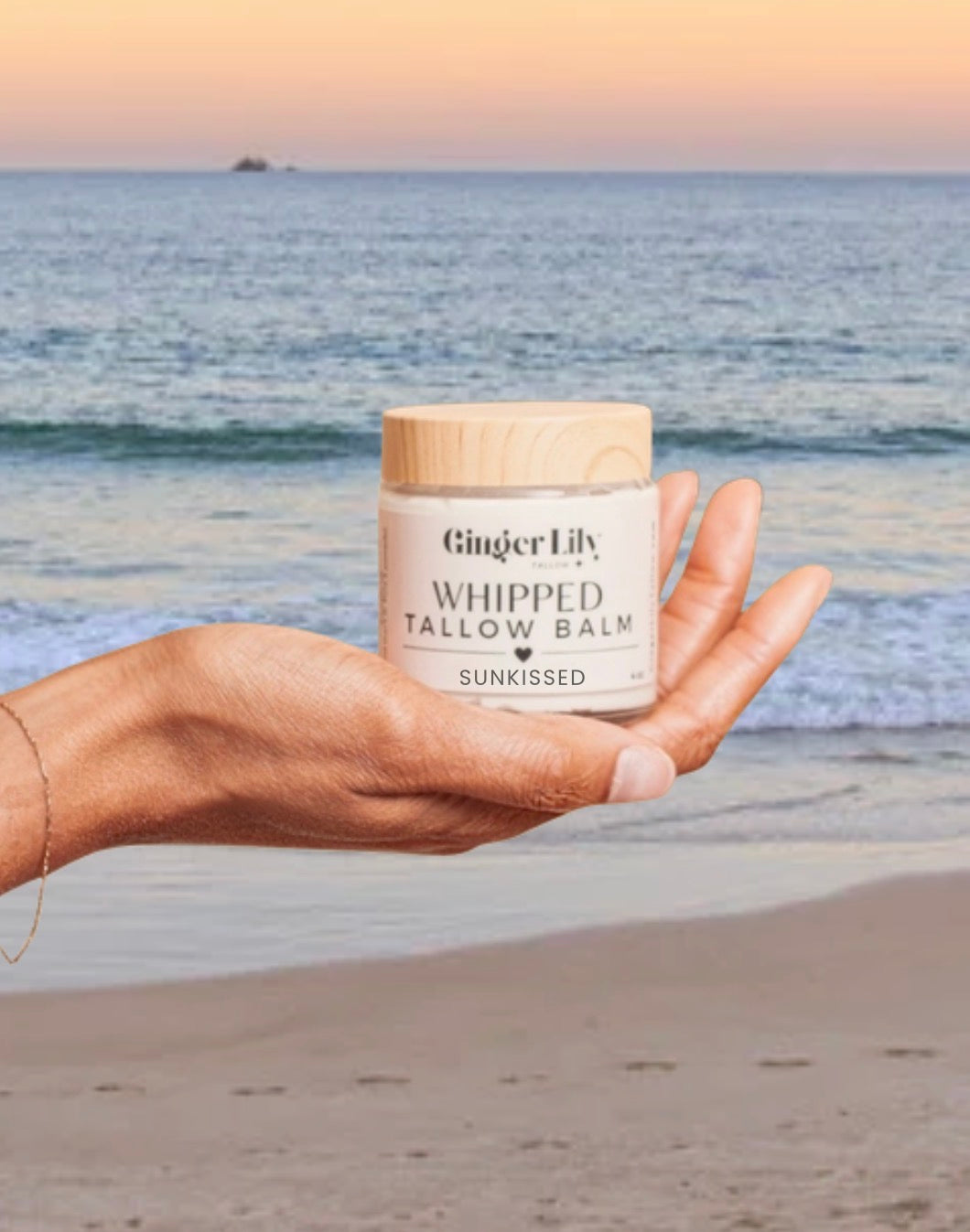 Organic Whipped Ginger Lily Tallow Balm in hand at the beach, 100% grass-fed organic beef tallow moisturizer for face and body, natural whipped balm for dry, sensitive skin with nourishing clean skincare and ocean sunset background.