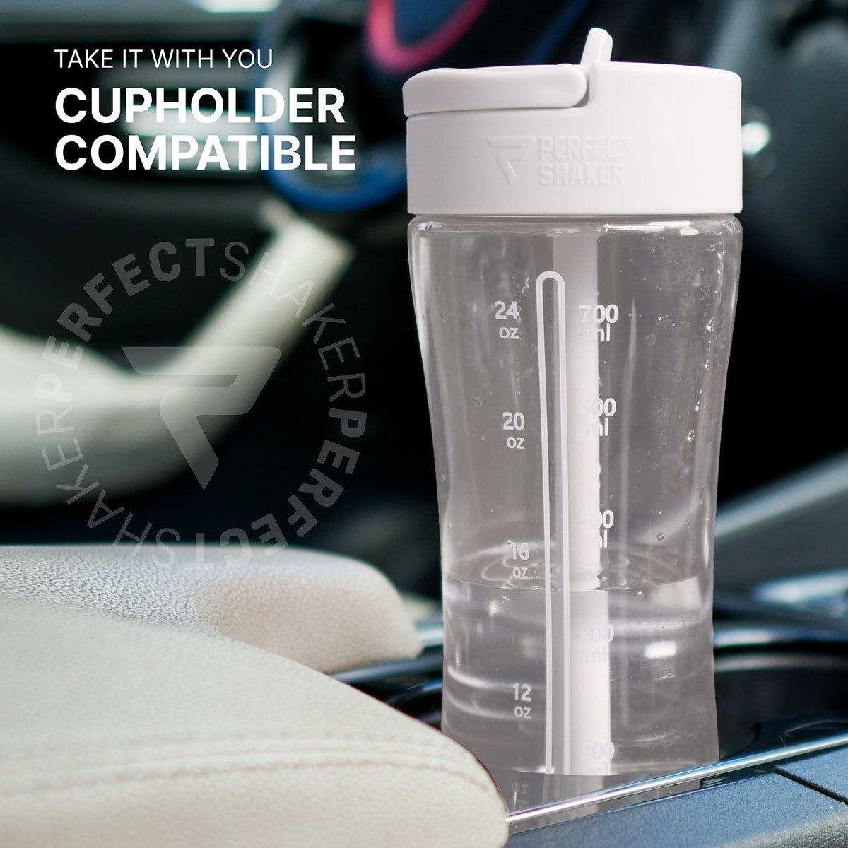A clear plastic shaker bottle with a white flip-top lid and integrated straw, shown sitting in a car cup holder. The bottle has printed measurement markings in ounces and liters.