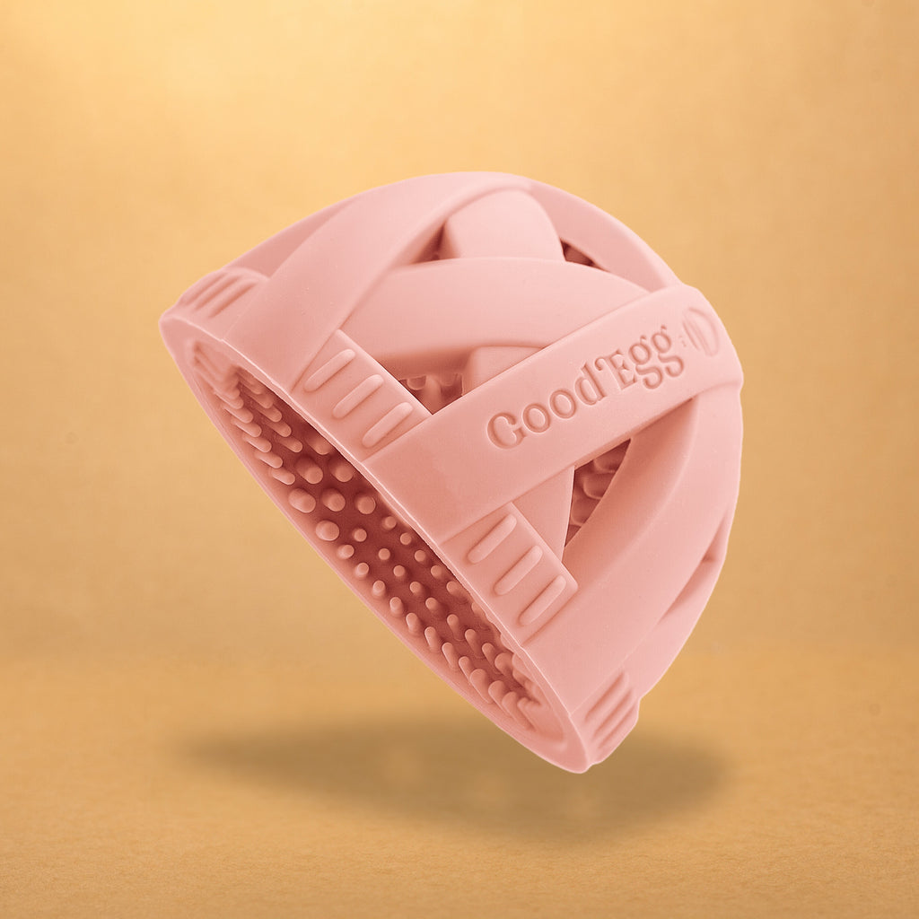 Original GoodEgg Brush™ silicone egg cleaning brush in soft pink with flexible textured scrubbing bristles, ergonomic cross-strap grip, and seamless food-safe design for gently cleaning fresh chicken, duck, and quail eggs.