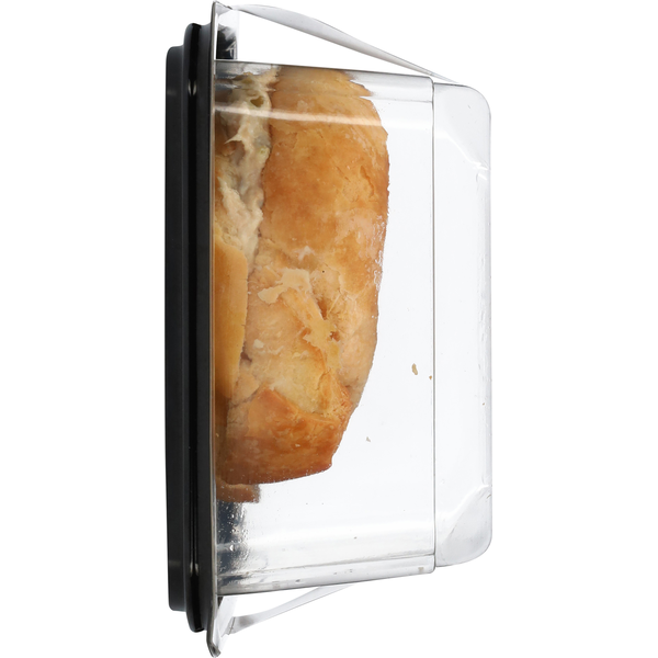 Side view of a fresh tuna salad croissant in a clear plastic deli container with a black base on a white background.